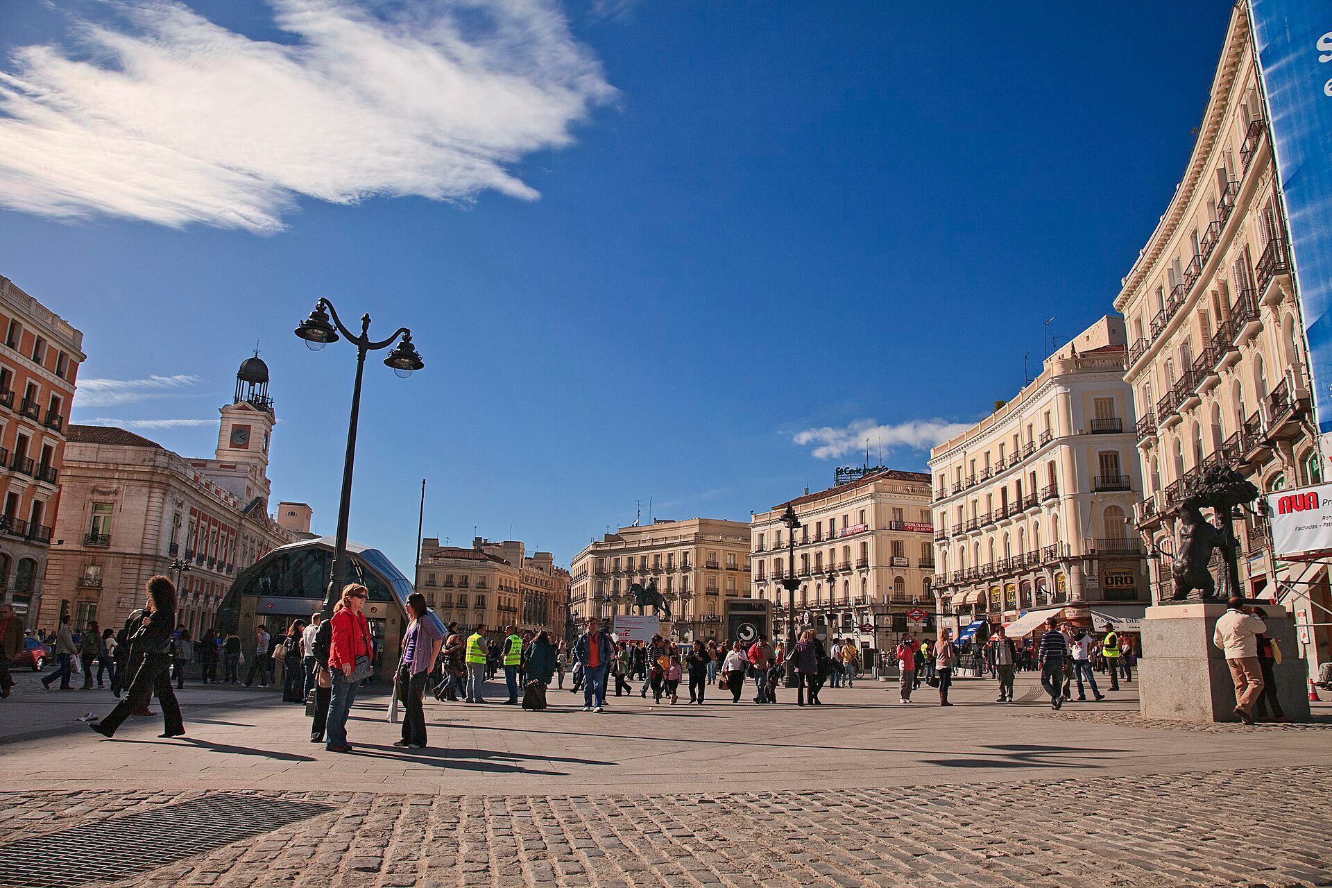 Puerta del Sol on a sunny day, with people crossing the square below the old post office clock tower.